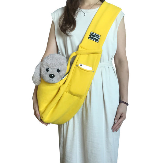 Person holding a yellow sling bag with a small gray dog inside on a white background