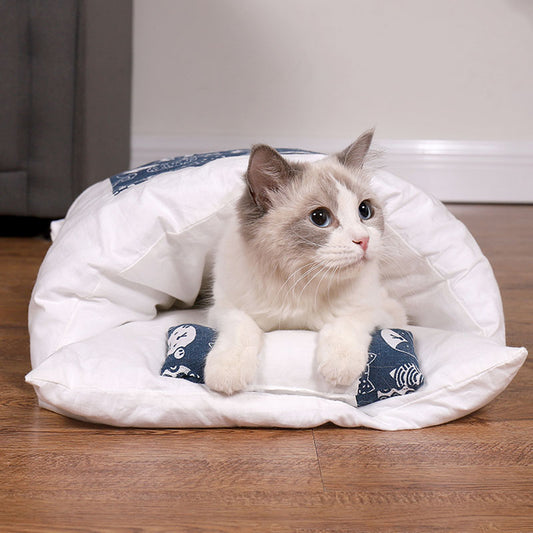 Cat lying on a white pet bed with blue patterns on a wooden floor.